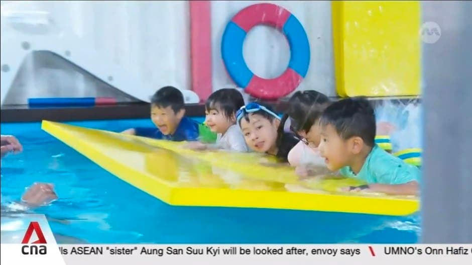Children smiling on a kickboard during a group swim class at Fabulous Swim