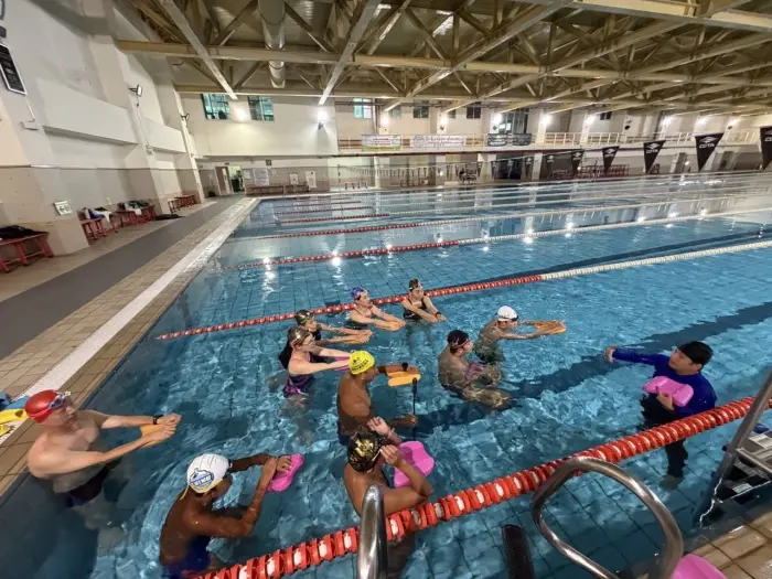 Coach trainees practising drills with kickboards in an indoor pool