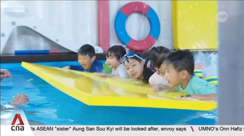 Children smiling on a kickboard during a group swim class at Fabulous Swim